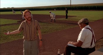 Movie still from “Field of Dreams” (1989), directed by Phil Alden Robinson – A group of men standing on top of a baseball field; Wide shot, Over the shoulder angle
