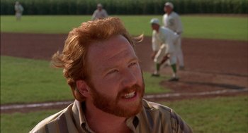 Movie still from “Field of Dreams” (1989), directed by Phil Alden Robinson – A person with a beard on a baseball field; Close Up shot, Over the shoulder angle