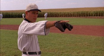 Movie still from “Field of Dreams” (1989), directed by Phil Alden Robinson – A baseball player is holding his mitt up to catch the ball; Medium shot, Over the shoulder angle