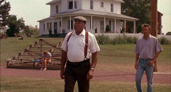 Movie still from “Field of Dreams” (1989), directed by Phil Alden Robinson – An older man standing in front of a house; Medium shot, Low angle