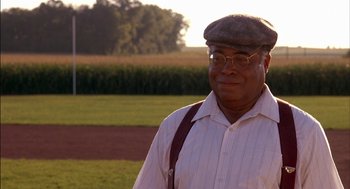 Movie still from “Field of Dreams” (1989), directed by Phil Alden Robinson – An older man wearing glasses and a hat; Medium shot, Low angle