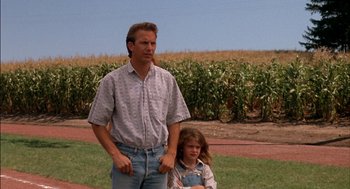Movie still from “Field of Dreams” (1989), directed by Phil Alden Robinson – A man standing next to a little girl in front of a corn field; Medium shot, Low angle