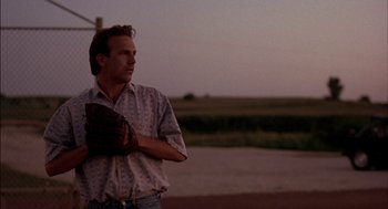 Movie still from “Field of Dreams” (1989), directed by Phil Alden Robinson – A man holding a catchers mitt on a baseball field; Medium shot, Low angle