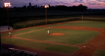 Movie still from “Field of Dreams” (1989), directed by Phil Alden Robinson – A baseball player standing on a baseball field at night; Extreme Wide shot, High angle