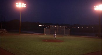 Movie still from “Field of Dreams” (1989), directed by Phil Alden Robinson – A baseball player standing on a baseball field at night; Extreme Wide shot, High angle