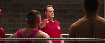 Movie still from “Fighting with My Family” (2019), directed by Stephen Merchant – A man in a boxing ring pointing at something; Medium shot, Over the shoulder angle