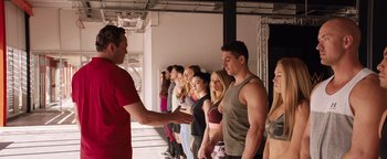 Movie still from “Fighting with My Family” (2019), directed by Stephen Merchant – A group of people standing in a line with a trainer; Medium shot, Over the shoulder angle