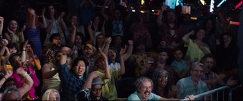 Movie still from “Fighting with My Family” (2019), directed by Stephen Merchant – A group of people sitting and standing in front of a crowd; Wide shot, High angle