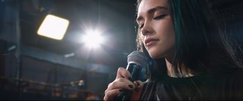 Movie still from “Fighting with My Family” (2019), directed by Stephen Merchant – A woman holding a microphone in front of her face; Close Up shot, Low angle