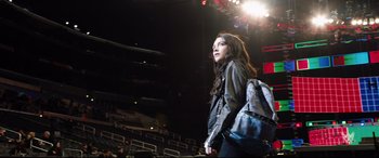 Movie still from “Fighting with My Family” (2019), directed by Stephen Merchant – A girl with a backpack is walking in a stadium; Wide shot, Low angle