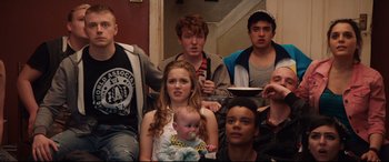 Movie still from “Fighting with My Family” (2019), directed by Stephen Merchant – A group of young people sitting next to each other; Medium shot, High angle