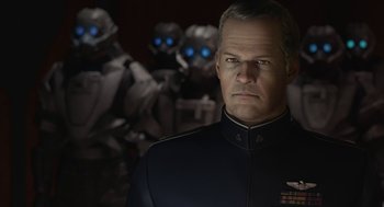 Movie still from “Final Fantasy: The Spirits Within” (2001), directed by Hironobu Sakaguchi – A man in a uniform standing in front of a group of robots; Close Up shot, Over the shoulder angle