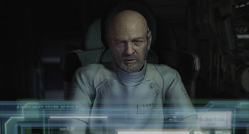Movie still from “Final Fantasy: The Spirits Within” (2001), directed by Hironobu Sakaguchi – A bald man in a white suit sitting in front of a computer screen; Close Up shot, Over the shoulder angle