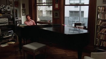 Movie still from “Fingers” (1978), directed by James Toback – A man sitting in front of a large black piano; Wide shot, High angle