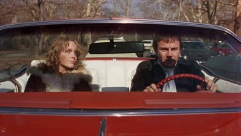 Movie still from “Fingers” (1978), directed by James Toback – A man and a woman sitting in the back seat of a red car; Medium shot, Low angle