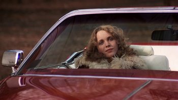 Movie still from “Fingers” (1978), directed by James Toback – A woman sitting in the driver's seat of a red car; Medium shot, Low angle