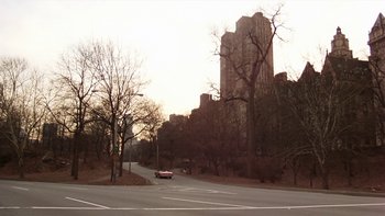 Movie still from “Fingers” (1978), directed by James Toback – A car driving down a street past tall buildings; Extreme Wide shot, High angle