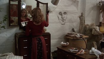 Movie still from “Fingers” (1978), directed by James Toback – A woman standing in front of a mirror in a room; Medium shot, Over the shoulder angle