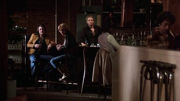 Movie still from “Fingers” (1978), directed by James Toback – A group of people sitting at a table with wine glasses; Wide shot, Low angle
