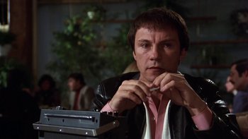 Movie still from “Fingers” (1978), directed by James Toback – A man sitting at a table with a cigarette in his mouth; Close Up shot, Low angle