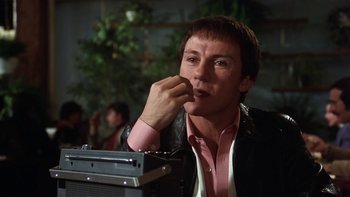 Movie still from “Fingers” (1978), directed by James Toback – A man sitting in front of an old radio; Close Up shot, Low angle