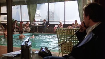 Movie still from “Fingers” (1978), directed by James Toback – A group of people sitting around a pool of water; Wide shot, High angle