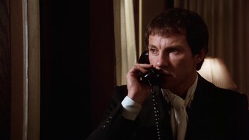 Movie still from “Fingers” (1978), directed by James Toback – A man talking on a phone while wearing a suit and tie; Close Up shot, Low angle