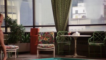 Movie still from “Fingers” (1978), directed by James Toback – A room filled with lots of furniture next to a large window; Wide shot, High angle