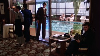 Movie still from “Fingers” (1978), directed by James Toback – A man standing in front of a swimming pool; Wide shot, High angle