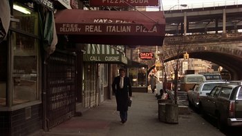 Movie still from “Fingers” (1978), directed by James Toback – A man walking down a street under a restaurant sign; Wide shot, Low angle