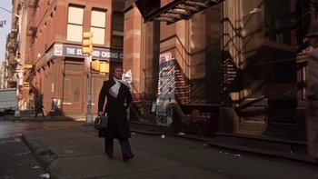 Movie still from “Fingers” (1978), directed by James Toback – A woman walking down the street holding a bag; Wide shot, Low angle