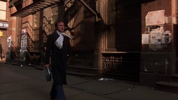 Movie still from “Fingers” (1978), directed by James Toback – A man walking down the street in a black coat; Wide shot, Low angle