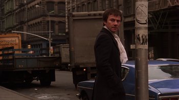 Movie still from “Fingers” (1978), directed by James Toback – A man standing next to a car on the side of the street; Medium shot, Low angle