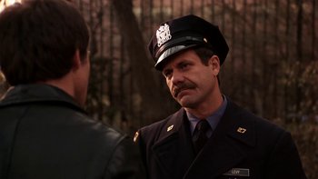 Movie still from “Fingers” (1978), directed by James Toback – A man in a police uniform talking to another man; Close Up shot, Over the shoulder angle