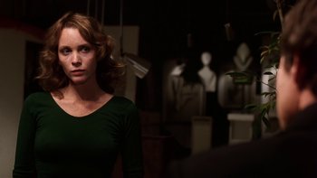 Movie still from “Fingers” (1978), directed by James Toback – A woman in a green shirt is standing in a room; Medium shot, Over the shoulder angle