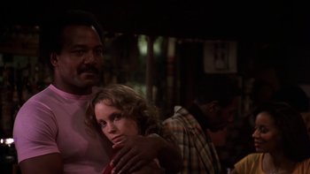Movie still from “Fingers” (1978), directed by James Toback – A man and a woman are standing next to each other; Medium shot, Low angle