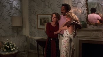 Movie still from “Fingers” (1978), directed by James Toback – Two women and a man standing in front of a fire place; Medium shot, Low angle