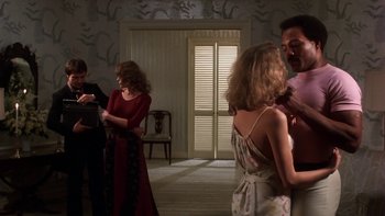 Movie still from “Fingers” (1978), directed by James Toback – A group of people standing around in a room; Medium shot, Over the shoulder angle