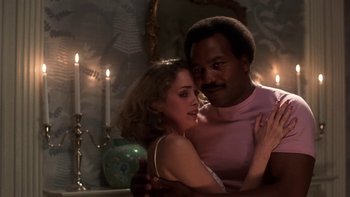 Movie still from “Fingers” (1978), directed by James Toback – A man and a woman embracing in front of candles; Medium shot, Low angle