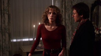 Movie still from “Fingers” (1978), directed by James Toback – A woman in a red dress standing next to a man in a red tie; Medium shot, Over the shoulder angle