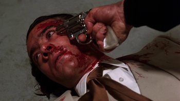 Movie still from “Fingers” (1978), directed by James Toback – A man with blood on his face holding a gun pointed at his face; Close Up shot, Low angle