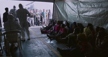 A group of people sitting in front of an open tent
