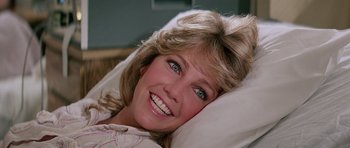 Movie still from “Firestarter” (1984), directed by Mark L. Lester – A person laying in a bed smiling; Close Up shot, High angle