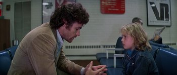 Movie still from “Firestarter” (1984), directed by Mark L. Lester – A man talking to a child in a waiting room; Medium shot, Over the shoulder angle