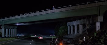 Movie still from “Firestarter” (1984), directed by Mark L. Lester – A man walking across a bridge over a freeway at night; Extreme Wide shot, High angle