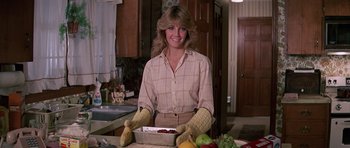 Movie still from “Firestarter” (1984), directed by Mark L. Lester – A woman in a kitchen holding a box of fruit; Medium shot, Low angle