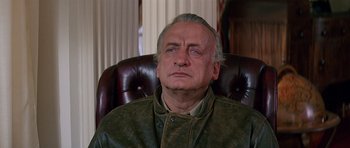 Movie still from “Firestarter” (1984), directed by Mark L. Lester – An older man sitting in a leather chair; Close Up shot, Low angle