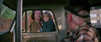 Movie still from “Firestarter” (1984), directed by Mark L. Lester – A man and a child in the back of a truck; Medium shot, Over the shoulder angle