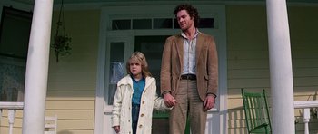 Movie still from “Firestarter” (1984), directed by Mark L. Lester – A man and a girl standing in front of a house; Medium shot, Low angle