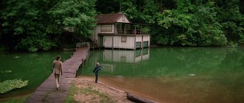 Movie still from “Firestarter” (1984), directed by Mark L. Lester – A person standing on a dock near a body of water; Extreme Wide shot, High angle